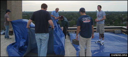 Jewish students from Texas A&M University affix tarp to a damaged roof at a Houston senior home. The project was arranged by their campus-based Chabad House.